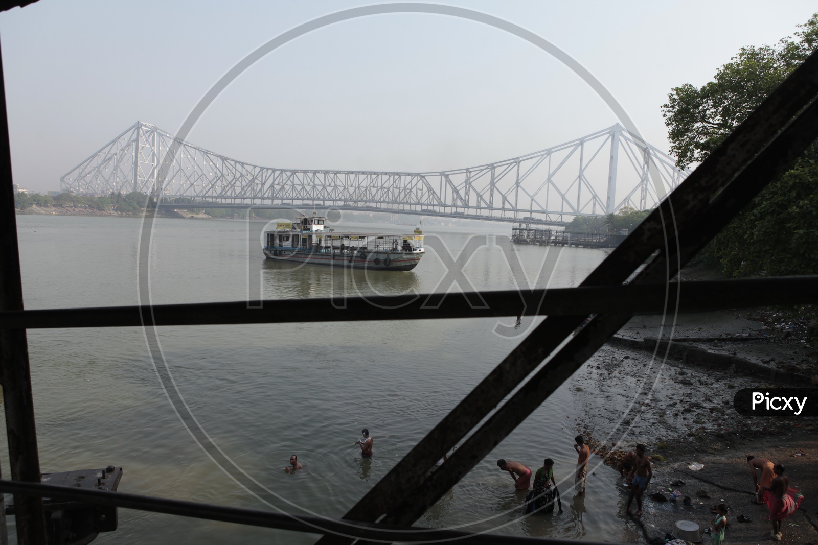 View of Howrah Bridge and people taking bath alongside the Hooghly River