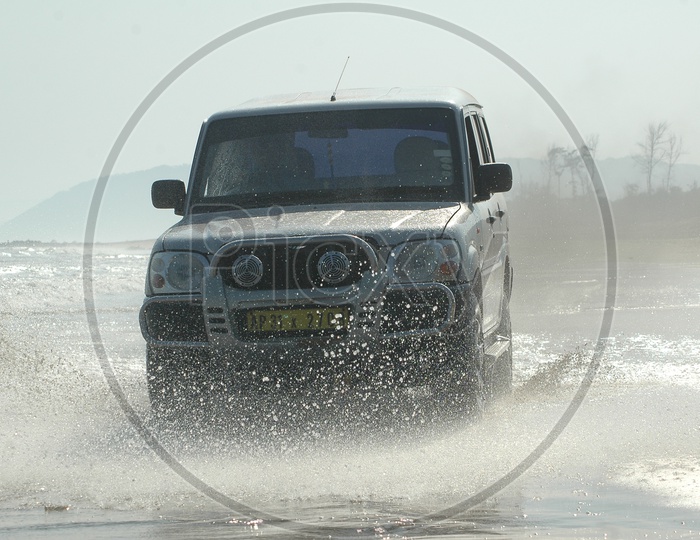 A Car Riding through The Sea Waves in a Beachh