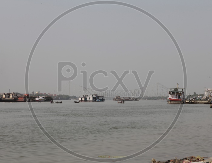 Boats and ships on the Hooghly River alongside the Howrah Bridge
