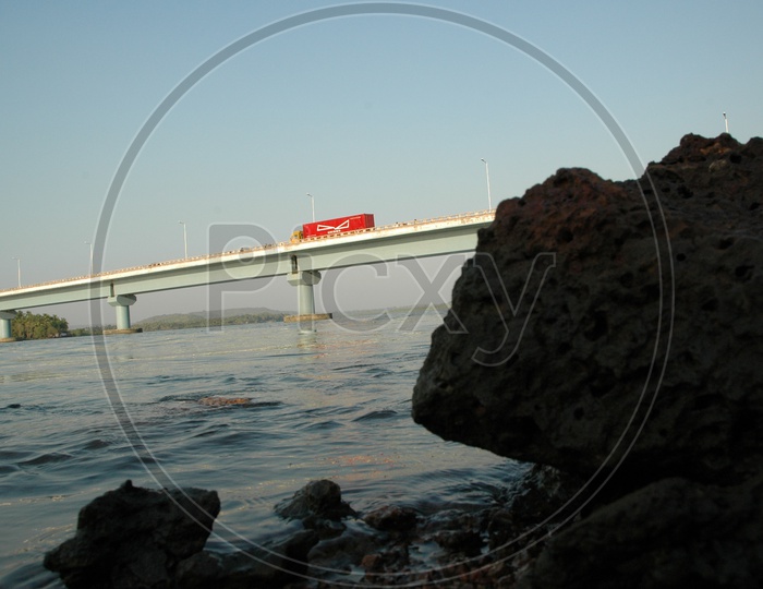 View of a moving truck on the Mandovi bridge from the banks of Mandovi river