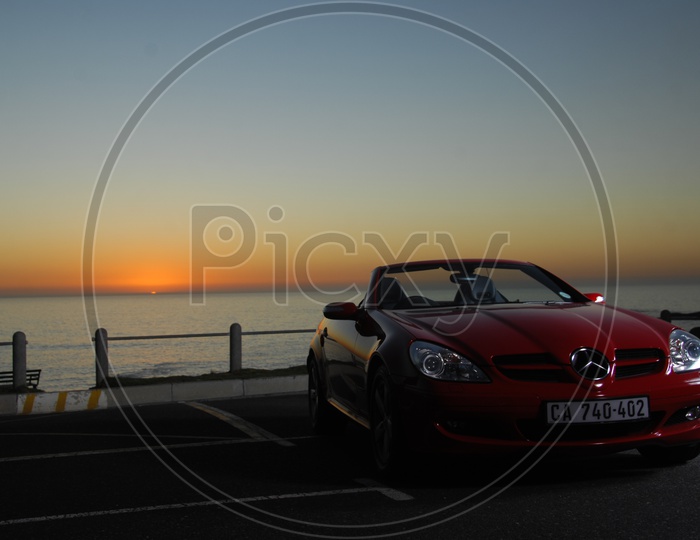 A  Benz Car parked At a Lake Front With Sunset Backdrop