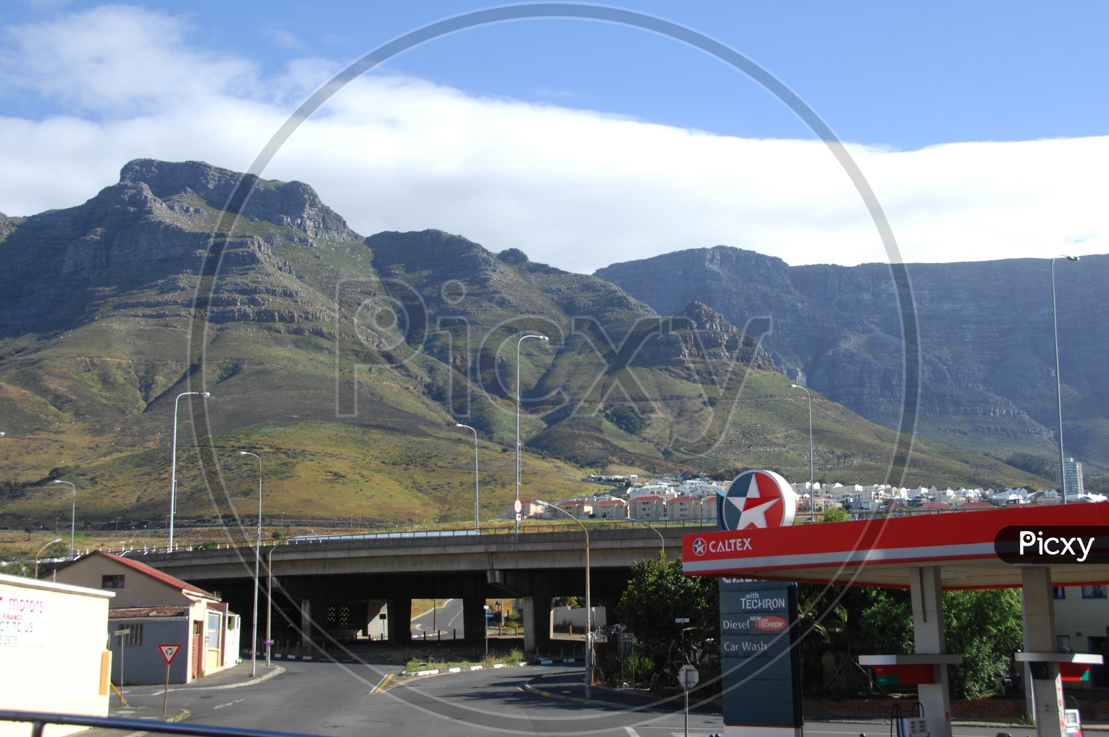 A gas filling station beside a bridge and mountains