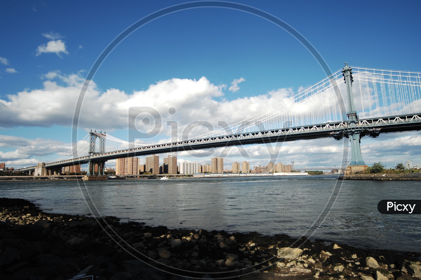 Manhattan Bridge over the East river as seen from Brooklyn with clouds in the blue sky