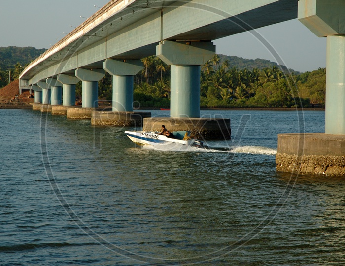 Speed boat in the Mandovi river and Pillars of the Mandovi Bridge