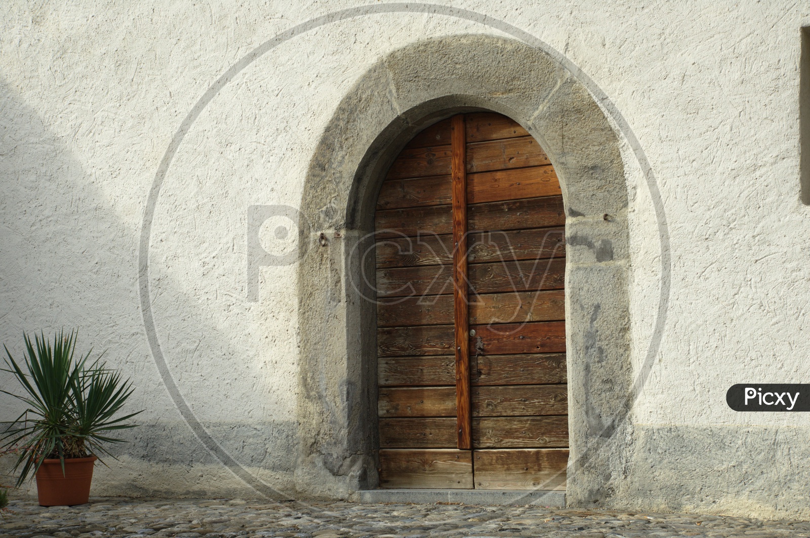 A arch like entrance of a building with wooden doors