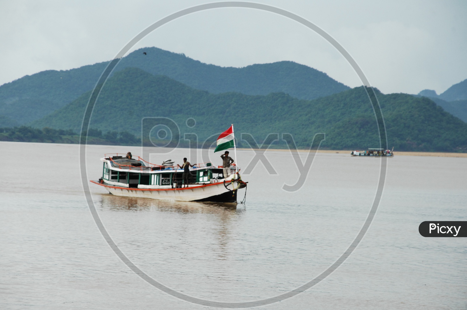 A boat with few people moving on a river with india flag in front of the boat