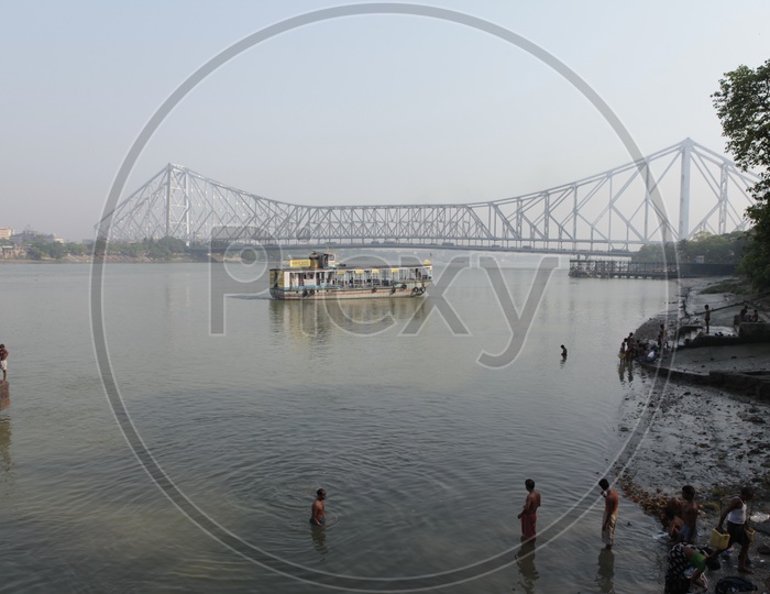 Local people taking bath in the Hooghly River alongside the Howrah Bridge