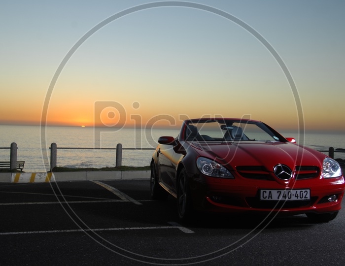 A  Benz Car parked At a Lake Front With Sunset Backdrop