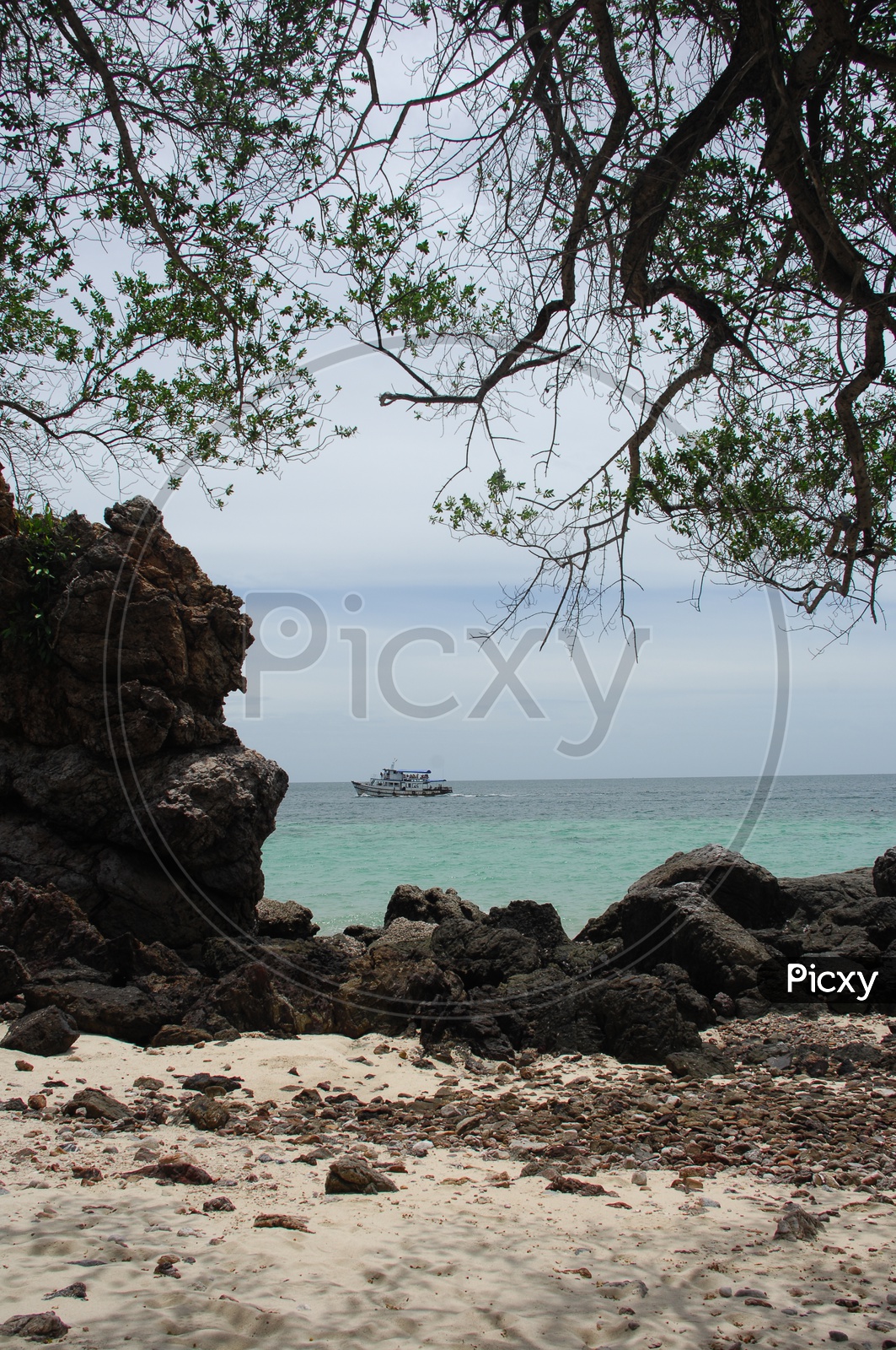 A boat seen at a distance in a beach through the rocks