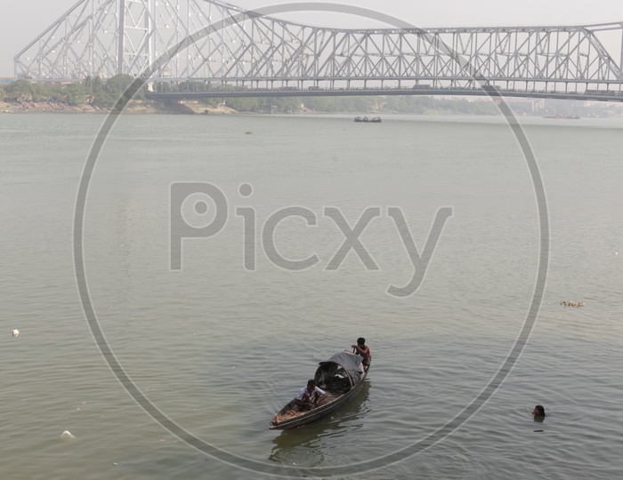 Small boat sailing in Kolkata with Howrah Bridge in the background