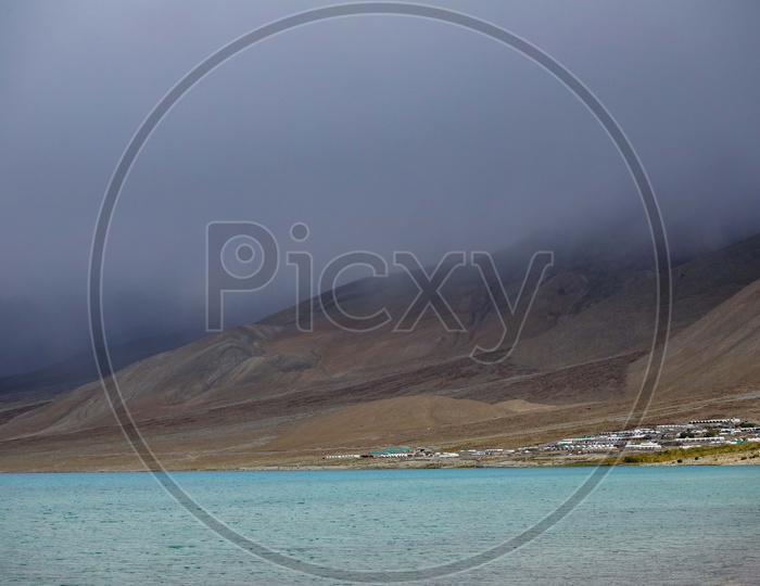 Pangong Lake alongside the mountains covered with dark clouds
