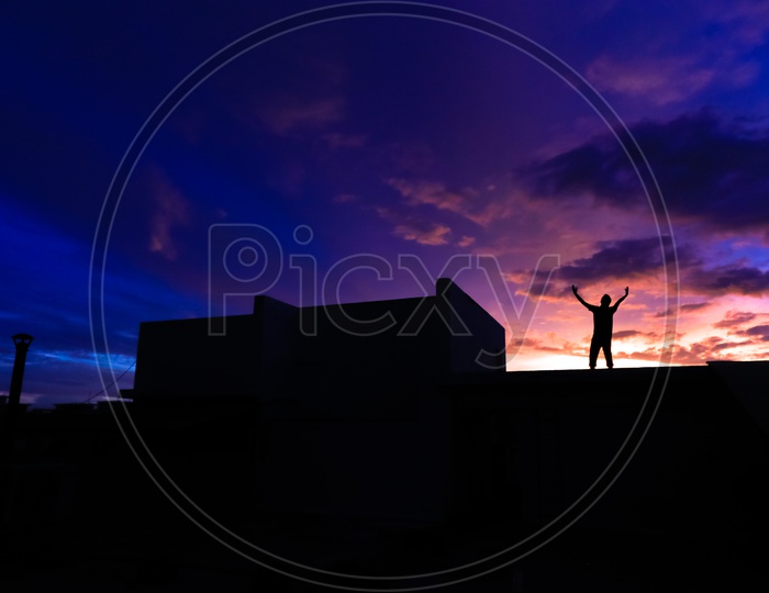 Silhouette of a Joyful Man Wide Spread his Arms over  a golden Hour Sky