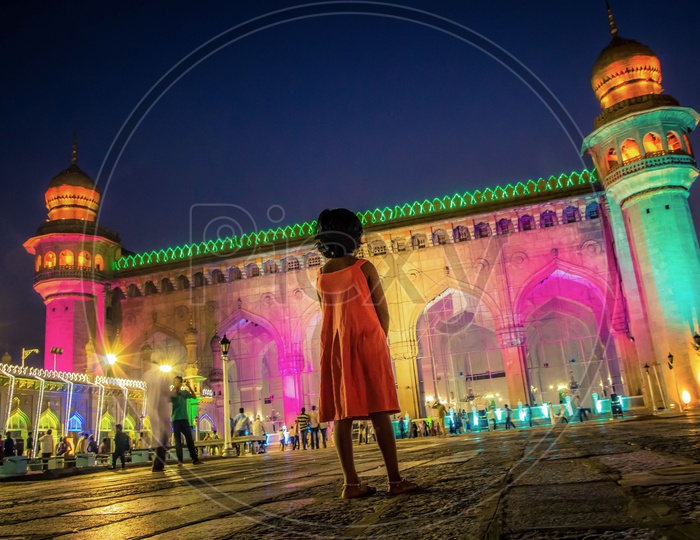 Little girl standing in front of the Mecca Masjid during night