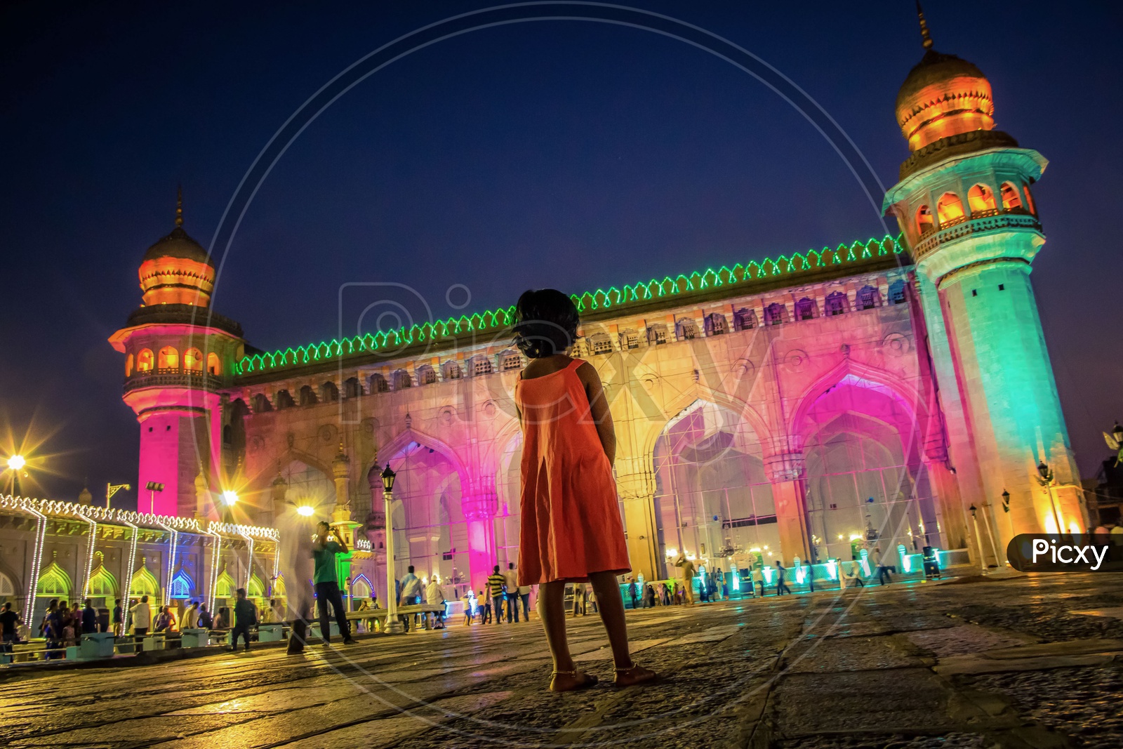 Little girl standing in front of the Mecca Masjid during night
