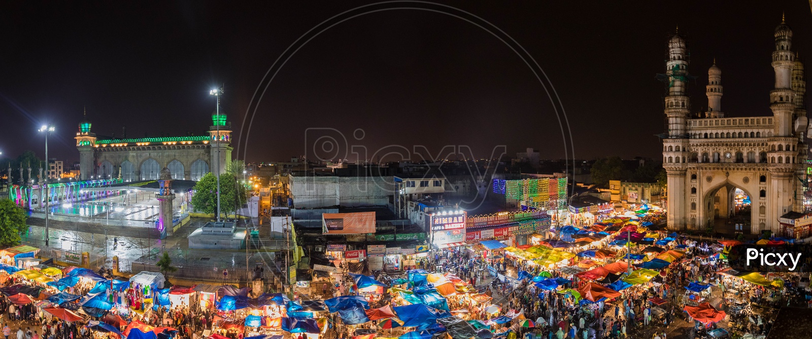 Panorama view of the crowd during night alongside the Mecca Masjid and Charminar