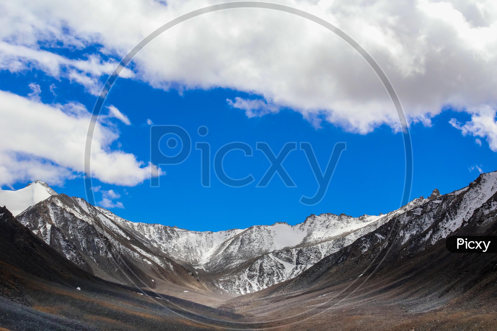 Snow covered Himalayan Mountains with blue sky and clouds in background