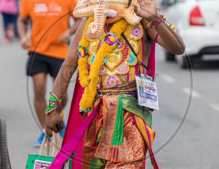 Indian Man Wearing Hindu God Ganesh Or Vinayaka Mask And Walking along The Road
