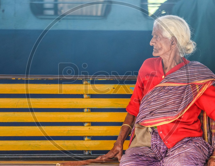 An Old Woman Sitting on a Bench In a Railway Station