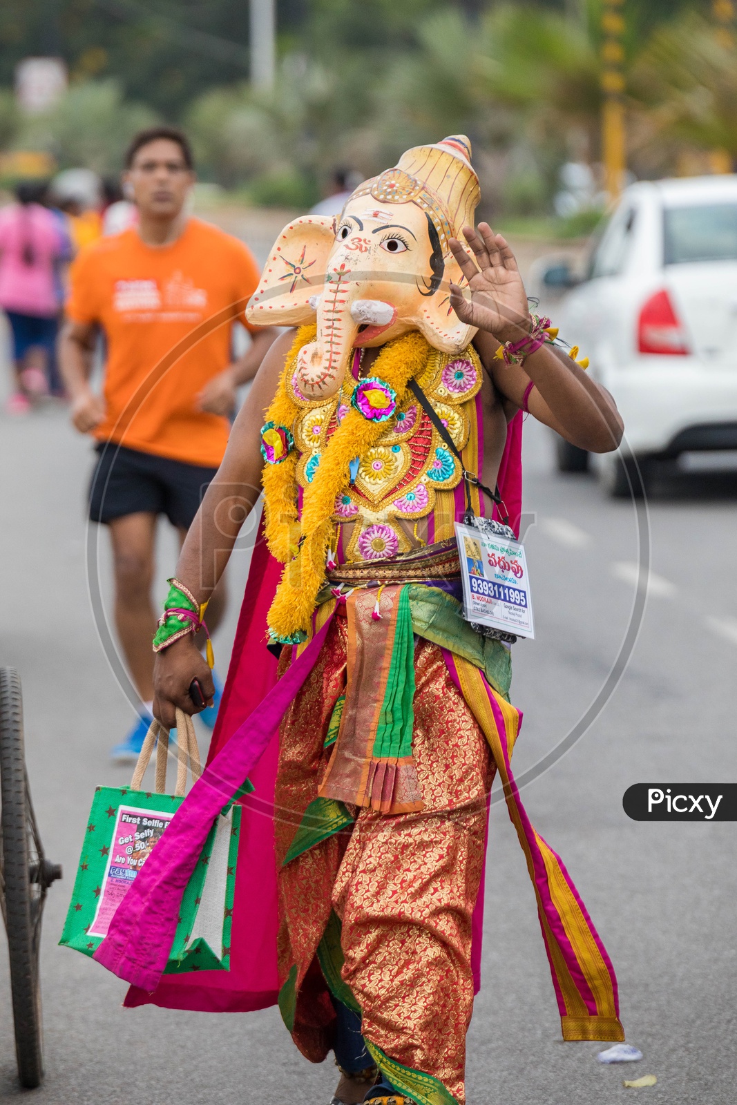 Indian Man Wearing Hindu God Ganesh Or Vinayaka Mask And Walking along The Road