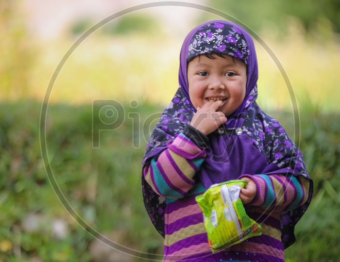 Portrait of a Himalayan girl kid eating chips