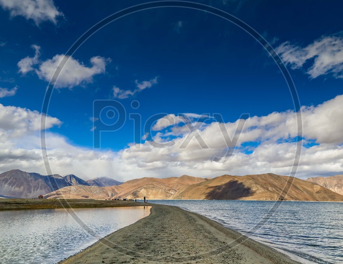 Landscape of a land separating the water alongside the mountains with blue sky
