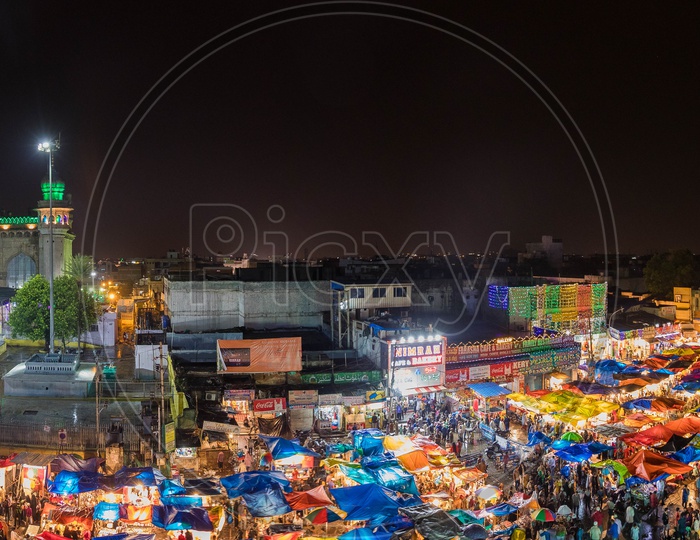Panorama view of the crowd during night alongside the Mecca Masjid and Charminar
