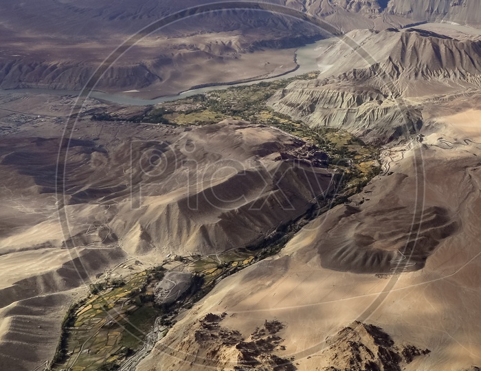 Aerial view of the Indus River alongside the crops and sandstone mountains