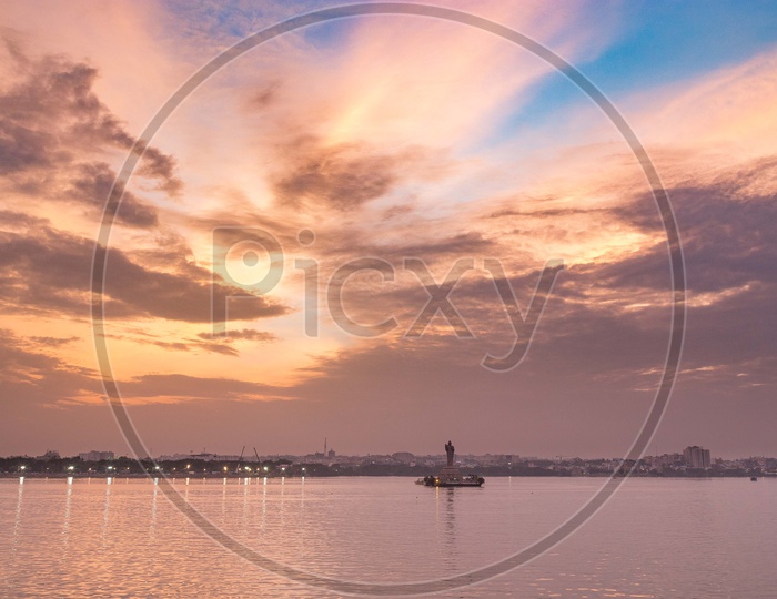 Buddhha Statue In Hussain sagar Lake With Dark Clouds and Golden Hour Sky In Background