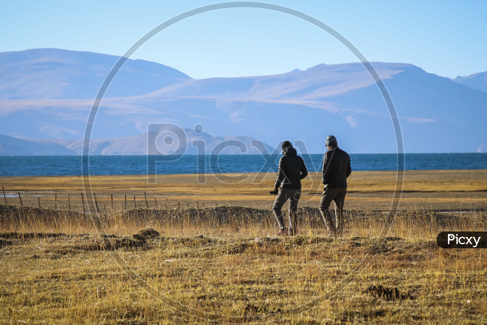 Couple walking along the plain land with the mountains in the background