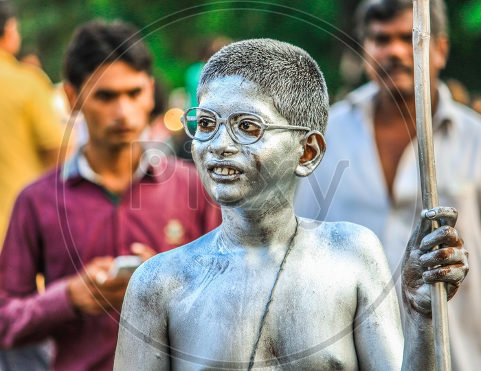Indian Boy Painted in Silver Colour And Standing Like Gandhi On Indian Streets