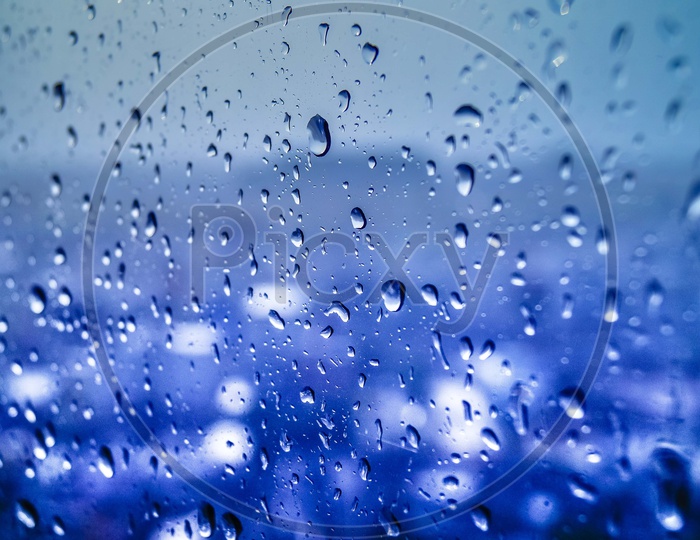 Texture of Water Droplets on a Glass over a Blue Luminous Light Background