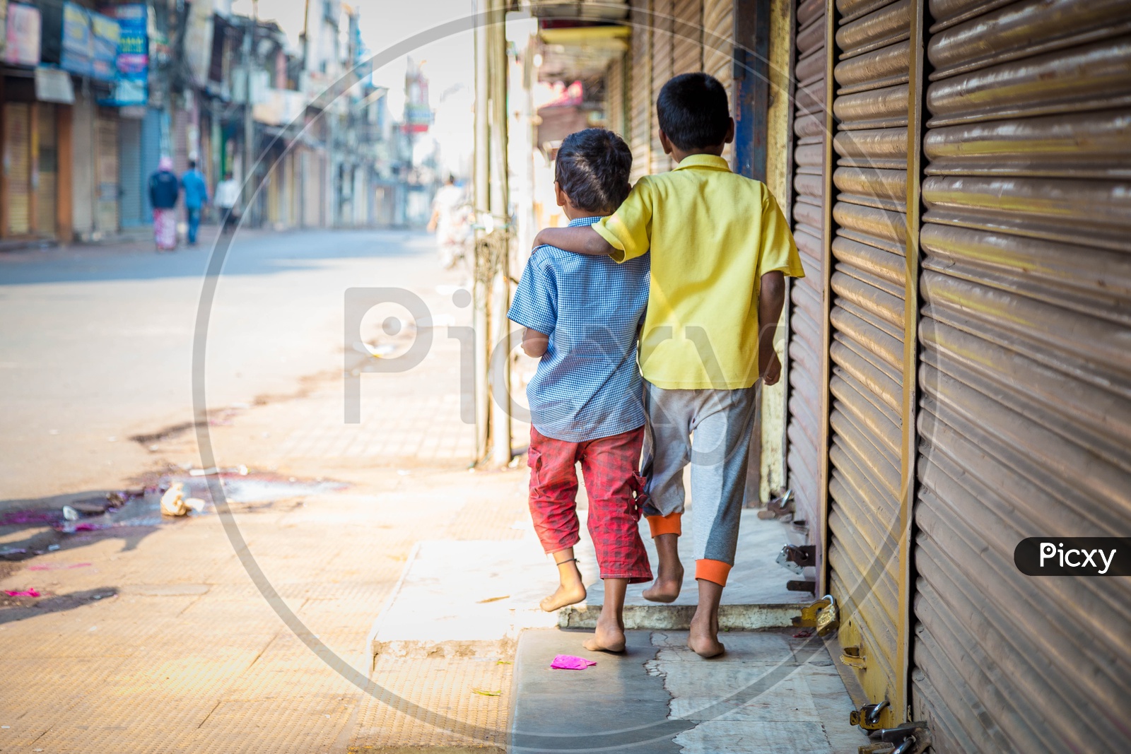 Two little kids walking by the shops in the street