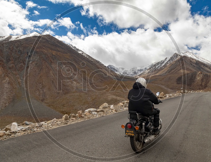 Royal Enfield Rider travelling on the roadway by the mountains