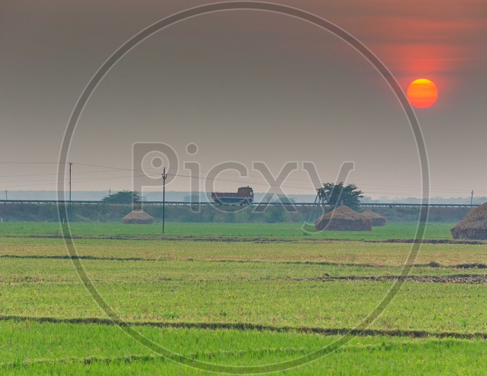 Sunset Over a Paddy Field With Highway Besides The Paddy Field