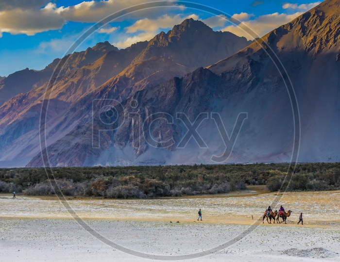 Landscape of travellers experiencing camel ride amidst mountains