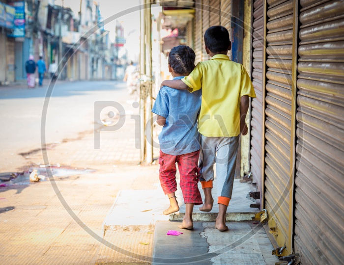 Two little kids walking by the shops in the street