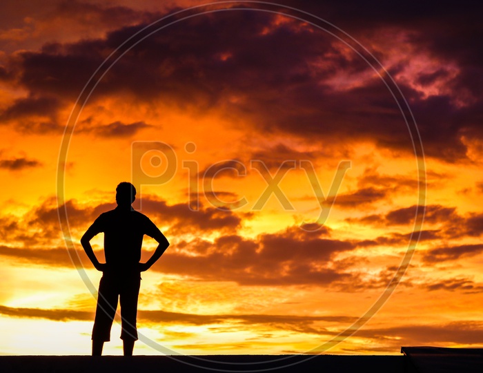 Silhouette Of a Man Standing Over a Golden Hour Sky With Clouds