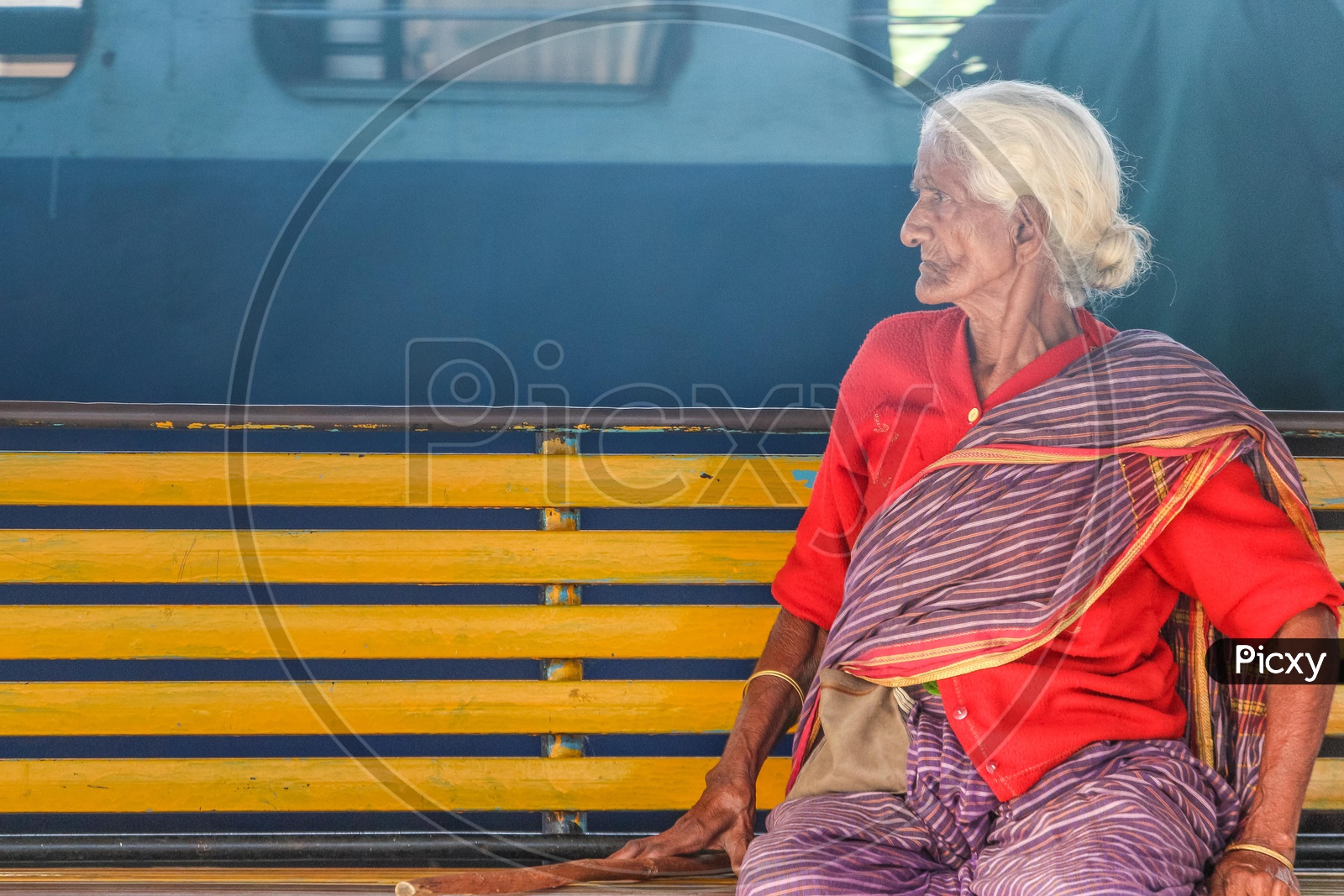 An Old Woman Sitting on a Bench In a Railway Station