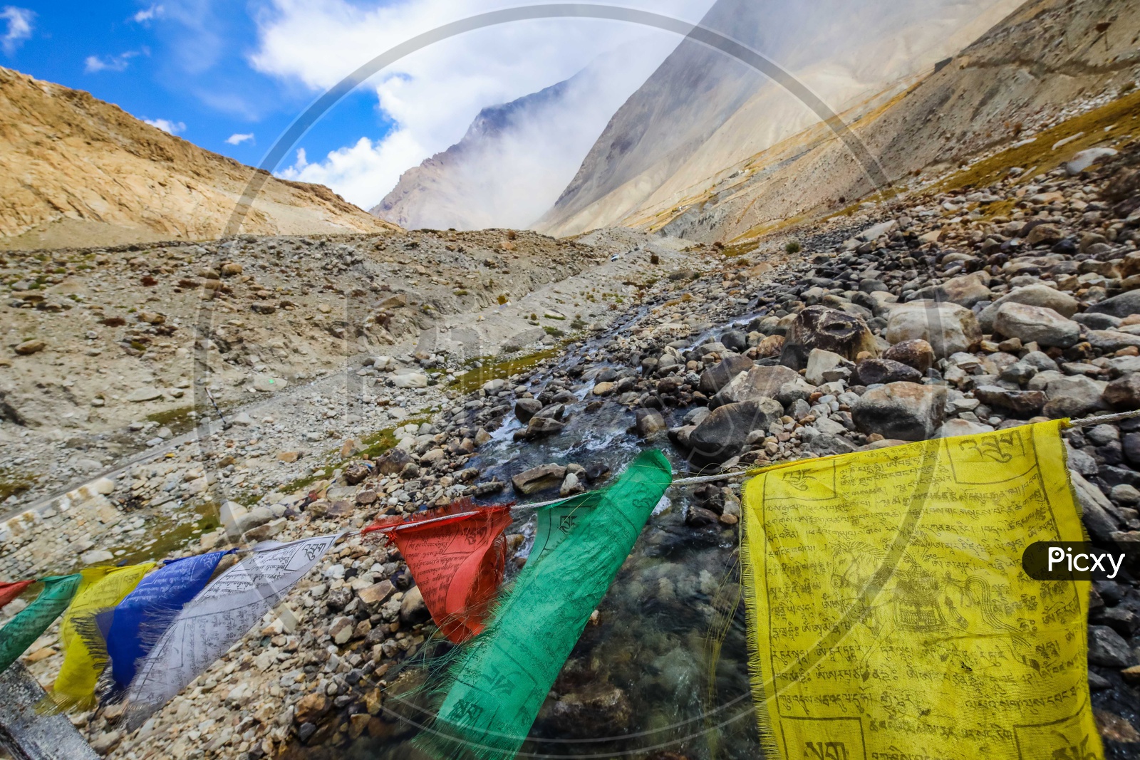 Buddhist Prayer Flags alongside the mountains and water flowing through the stream