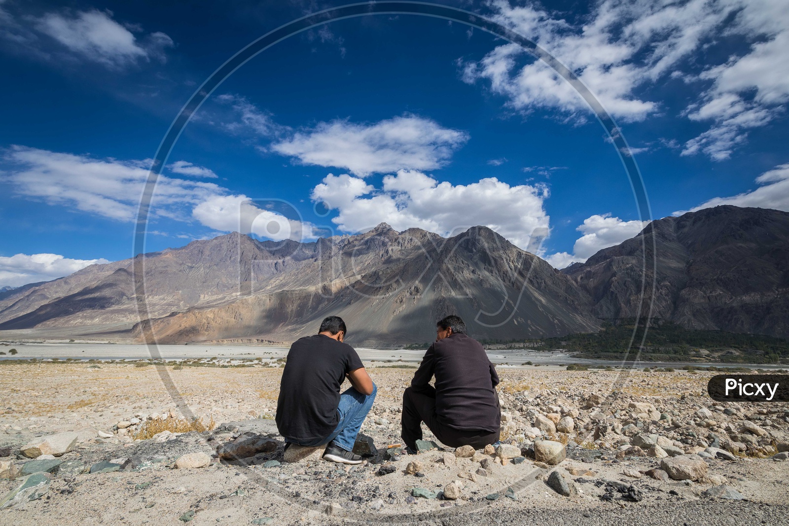 Two men sitting in front of the moutains