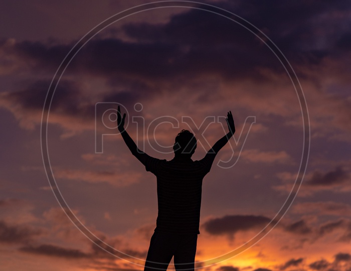 Silhouette of a Joyful Man over a golden red Sky Background