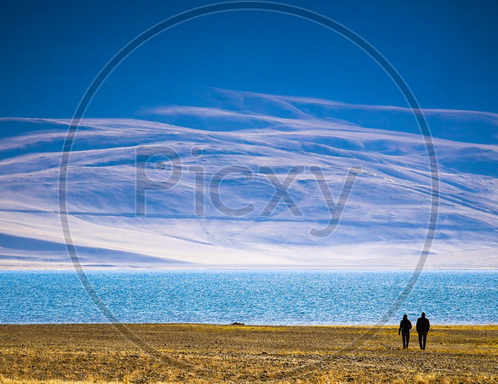 Couple taking a walk on the grassland alongside the Pangong lake with mountains in background