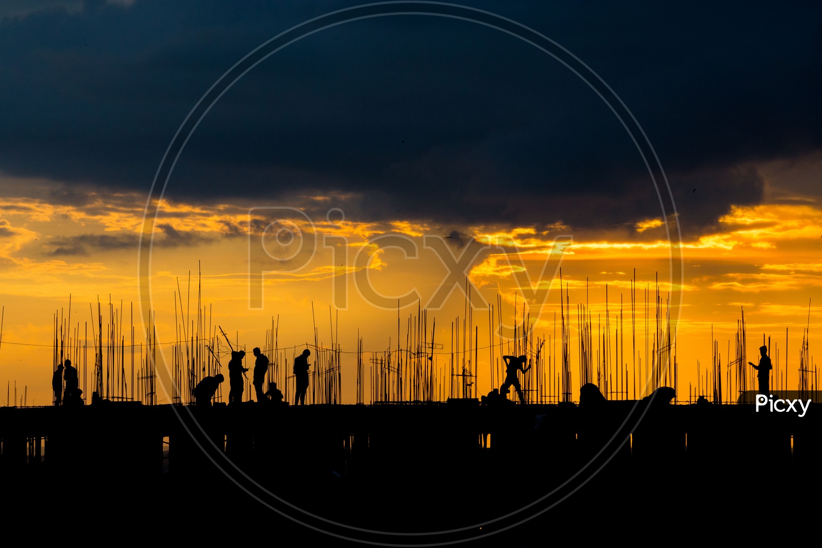 Silhouettes of A Construction Site With Workers On the Roof Top And with Golden Yellow Sky in Background