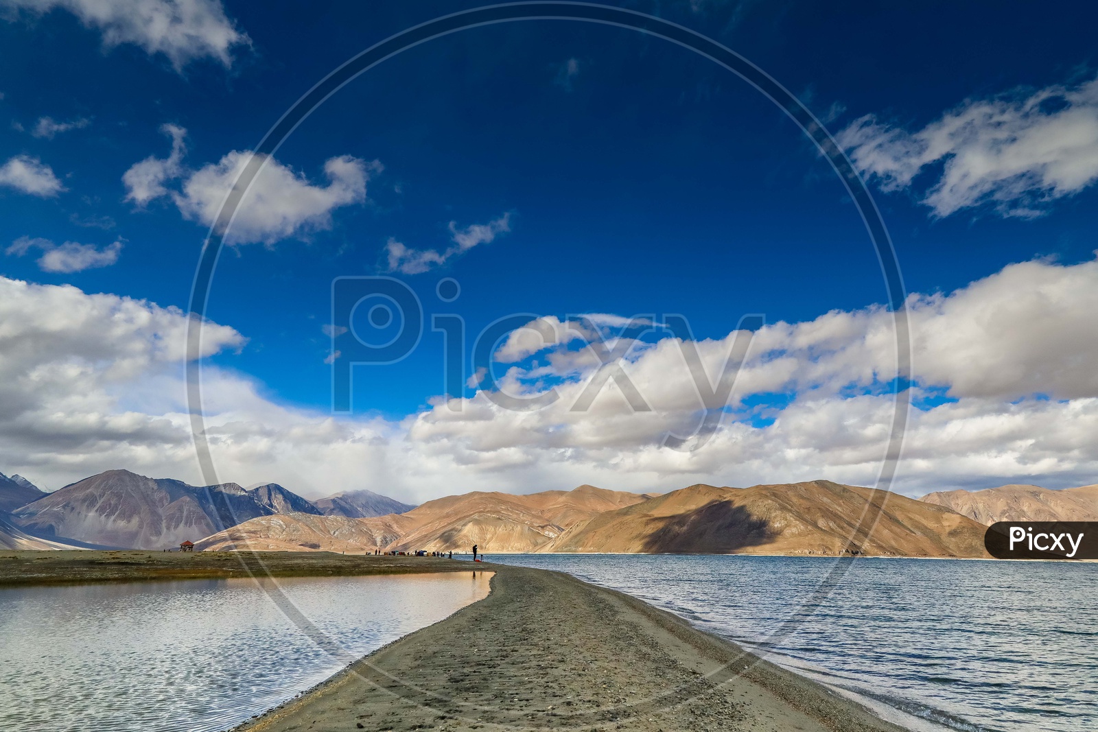 Landscape of a land separating the water alongside the mountains with blue sky