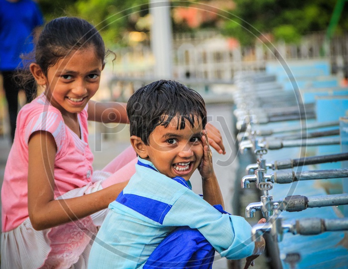 Portrait Of A Siblings At A Water Pond With Taps And smiling