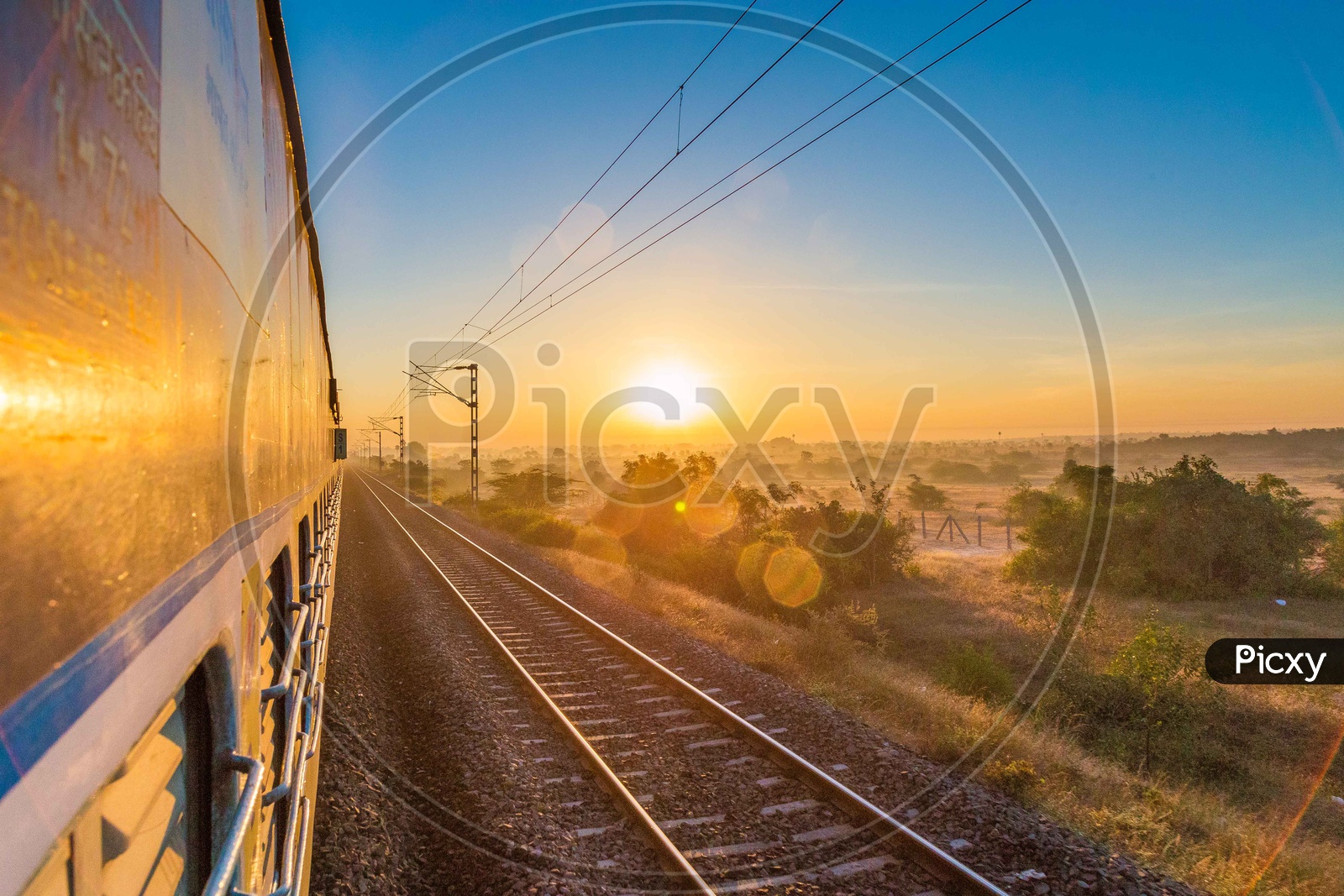 Sunset From a Moving train With Track And Electricity Poles