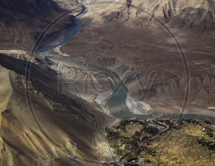 Aerial view of the Indus River flowing through the mountains alongside the crops