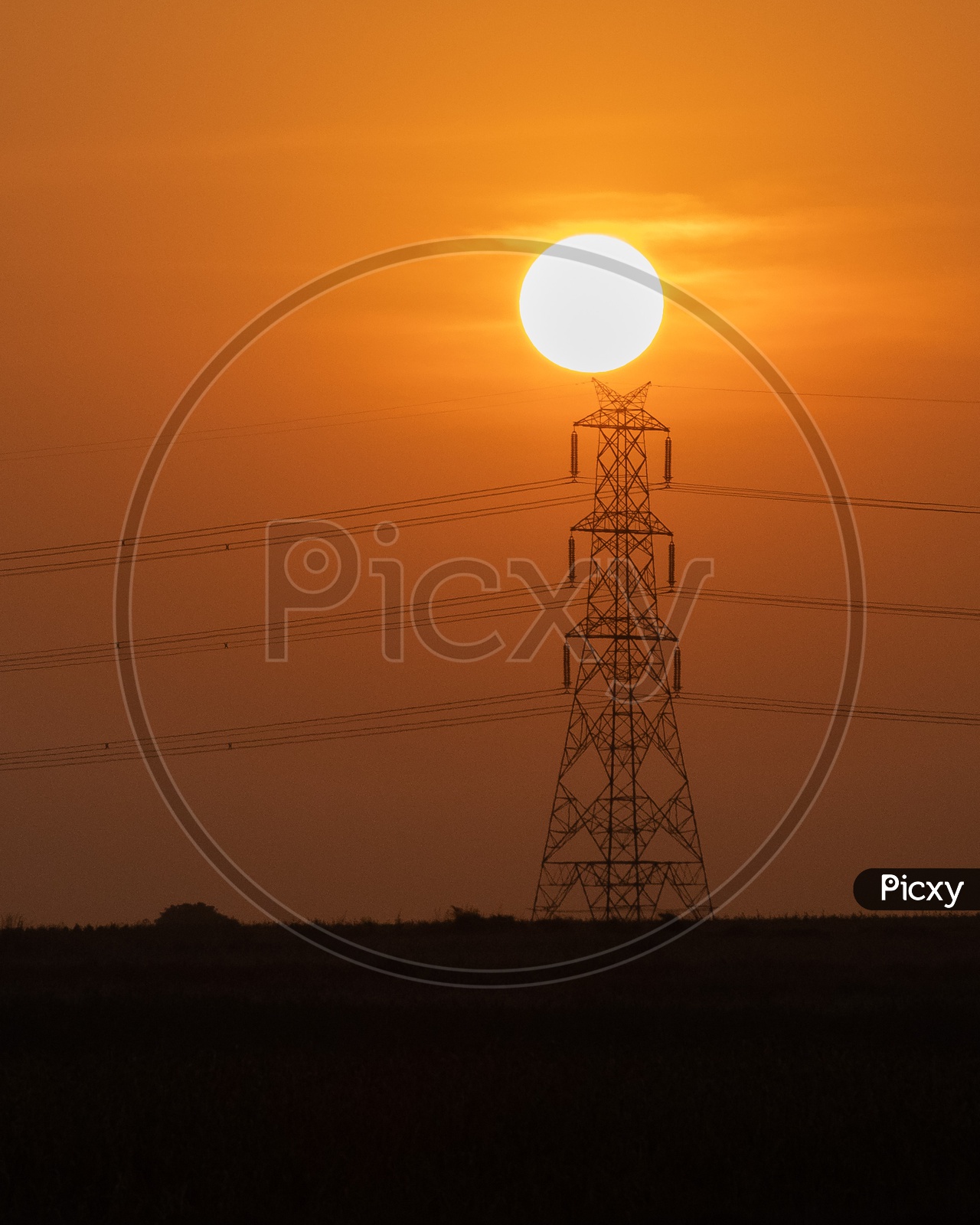 Silhouette Of A High Tension Electricity  Pole With Electricity Wire Wth a Golden Hour Sky And Sun In Background