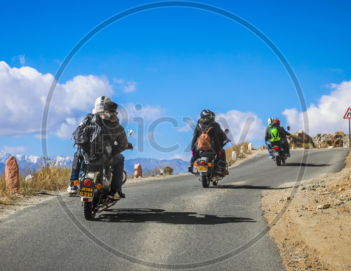 Travellers on three motorcycles by the roadway through the hills