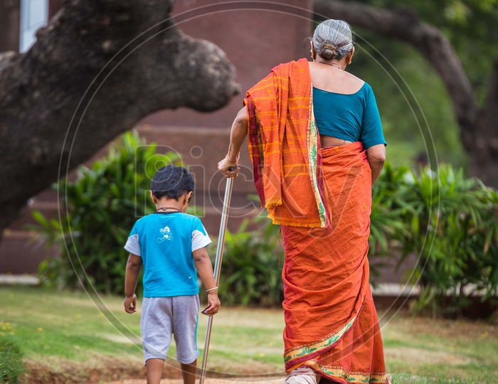 An Old Woman  Walking along With Her Grand Child in  a Park